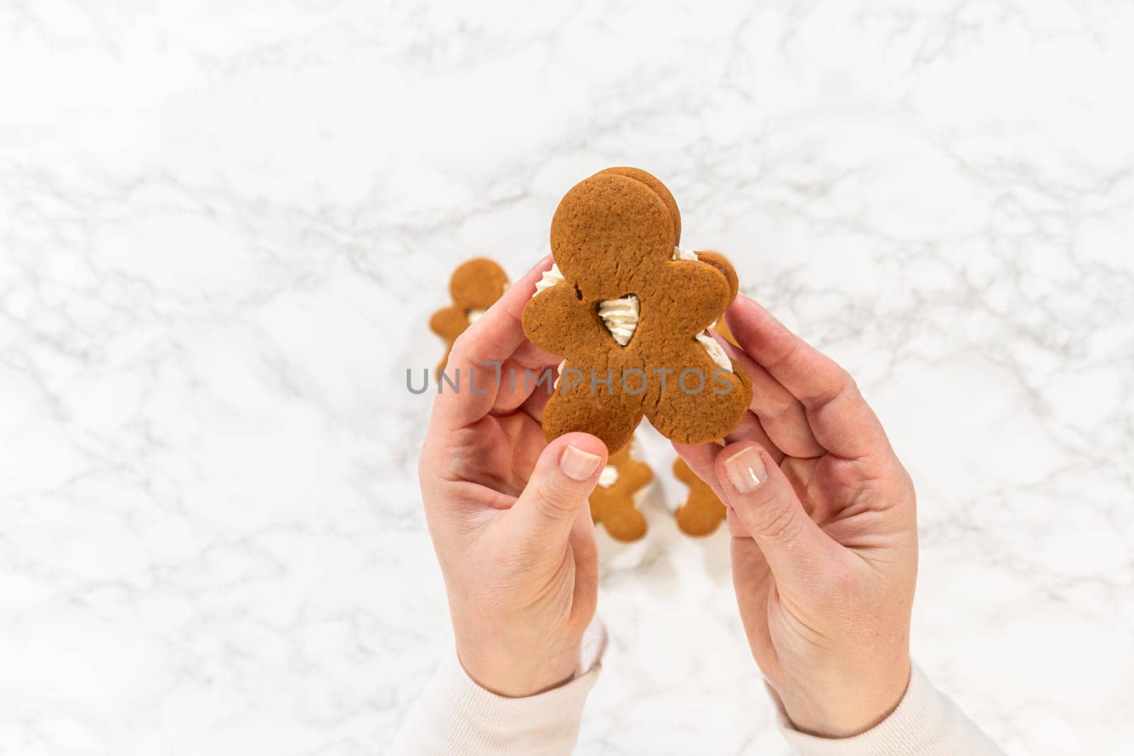 Flat lay. Gingerbread cookies filled with eggnog buttercream stand out, their rich hue complementing the eggnog buttercream, against a gentle background. These festive treats exude a homemade allure.