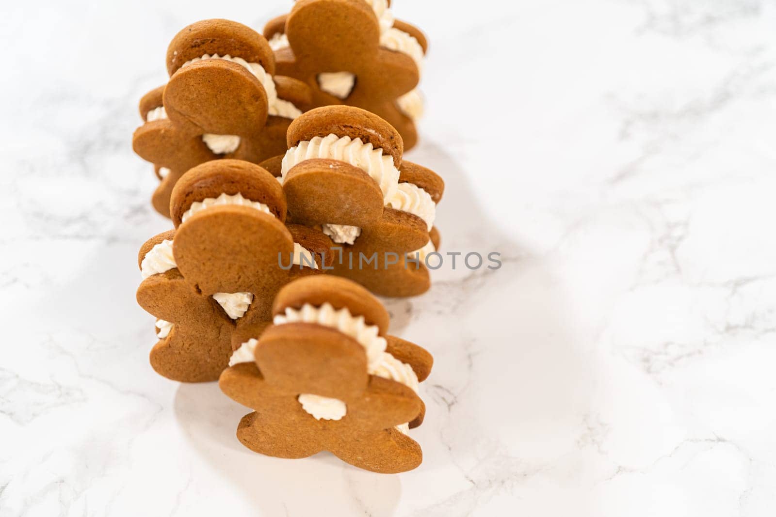 Gingerbread cookies filled with eggnog buttercream stand out, their rich hue complementing the eggnog buttercream, against a gentle background. These festive treats exude a homemade allure.
