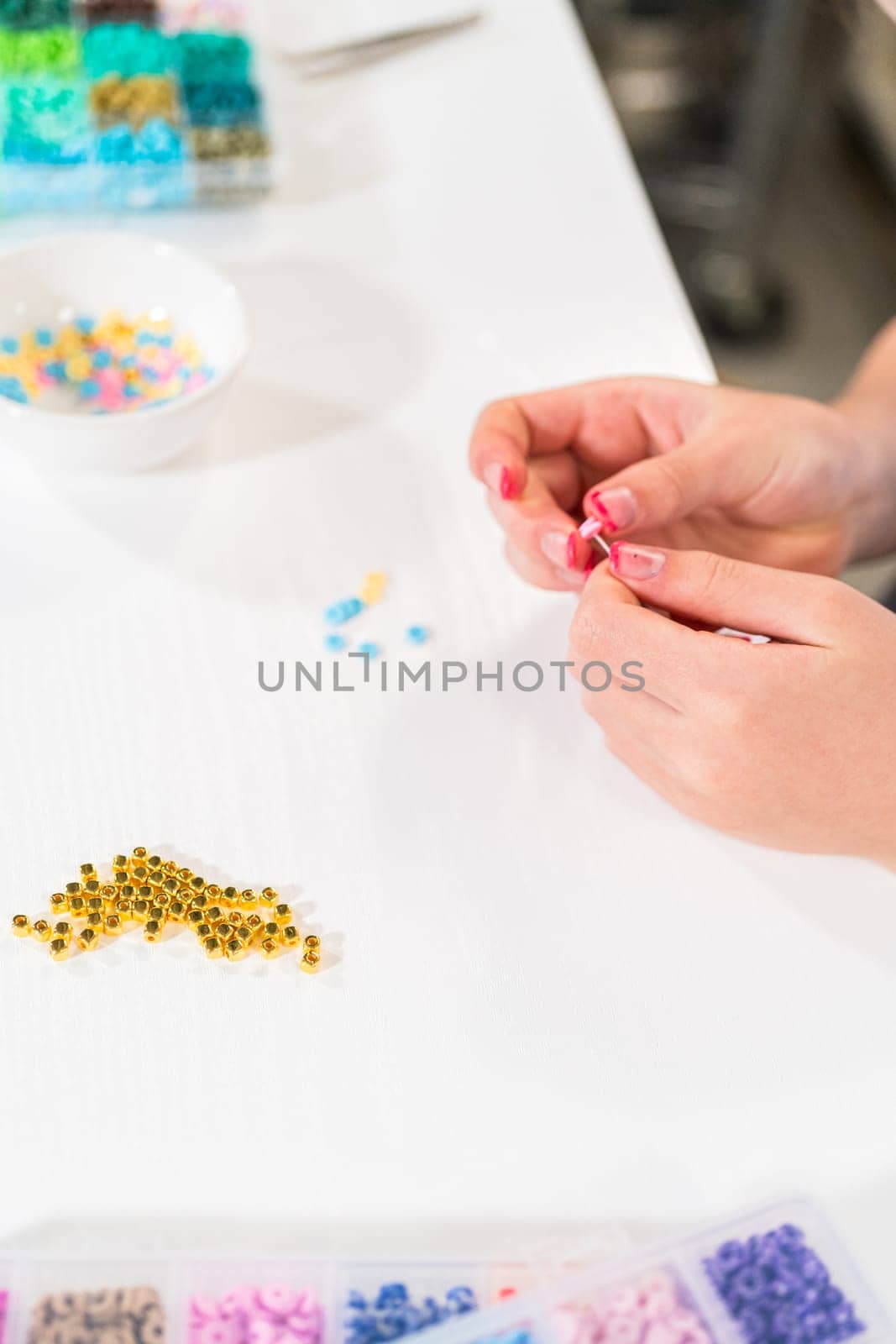 Little girl enjoys crafting colorful bracelets with vibrant clay beads set.