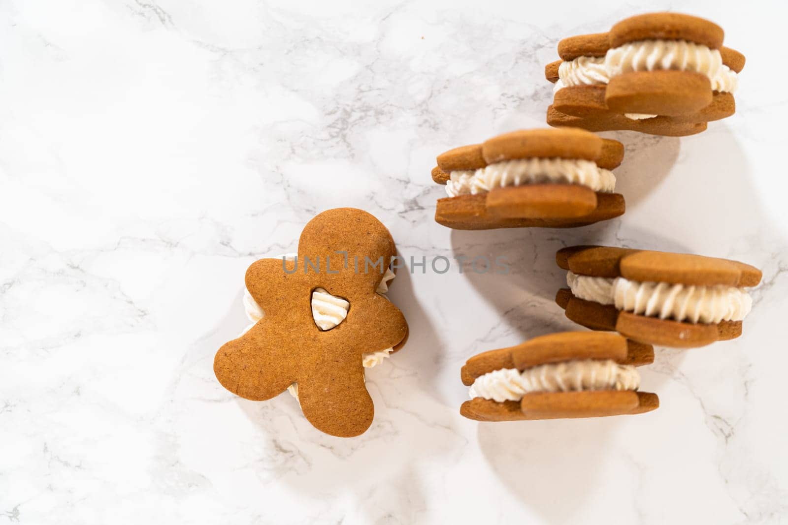 Gingerbread cookies filled with eggnog buttercream stand out, their rich hue complementing the eggnog buttercream, against a gentle background. These festive treats exude a homemade allure.