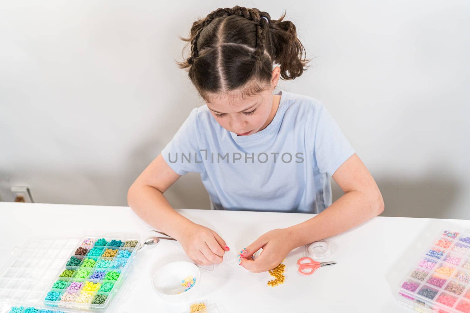 Little girl enjoys crafting colorful bracelets with vibrant clay beads set.
