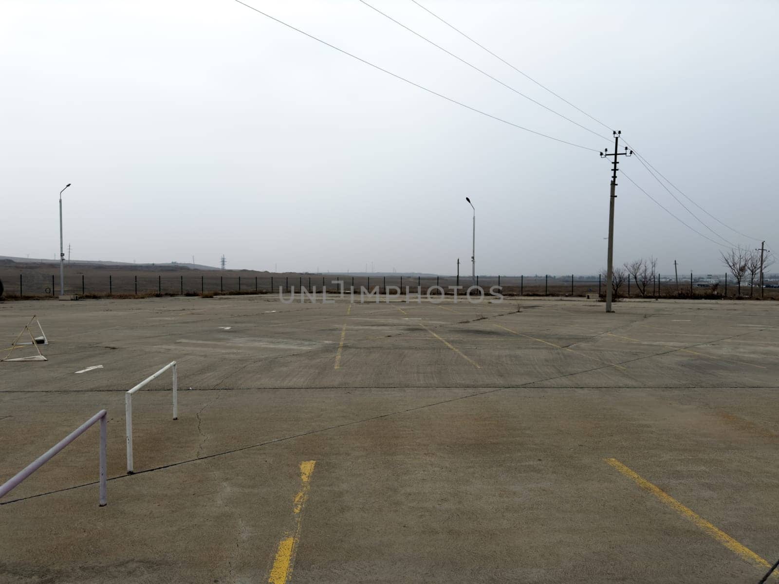 Empty street parking for cars with concrete pavement and markings for parking spaces. Large area for cars without anyone. Country parking for car exhibition, area for parking and displaying cars