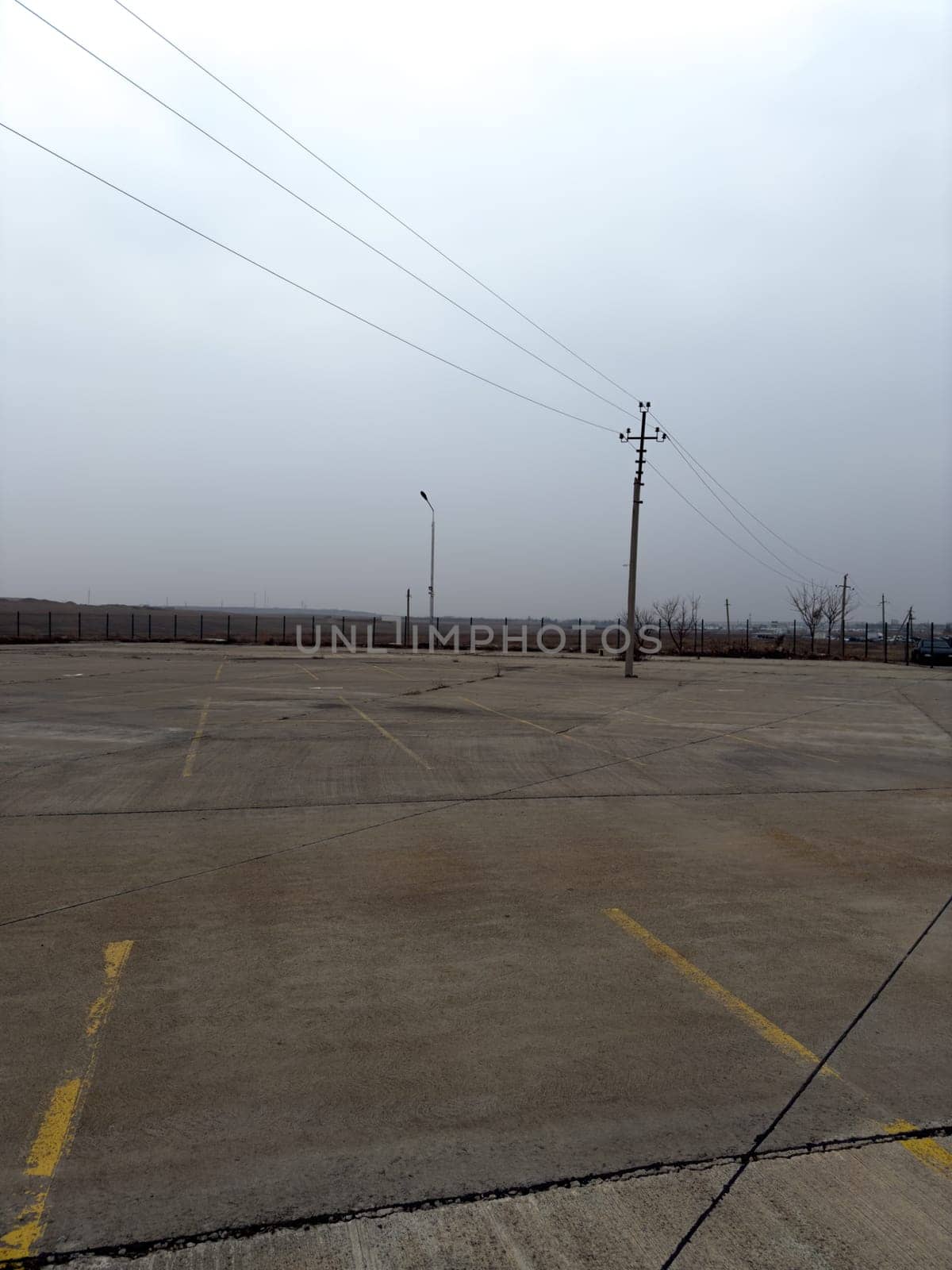Vertical photograph of old abandoned car parking lot. Empty parking lot for cars with markings for parking spaces on street. Large parking lot with concrete surface for cars is empty