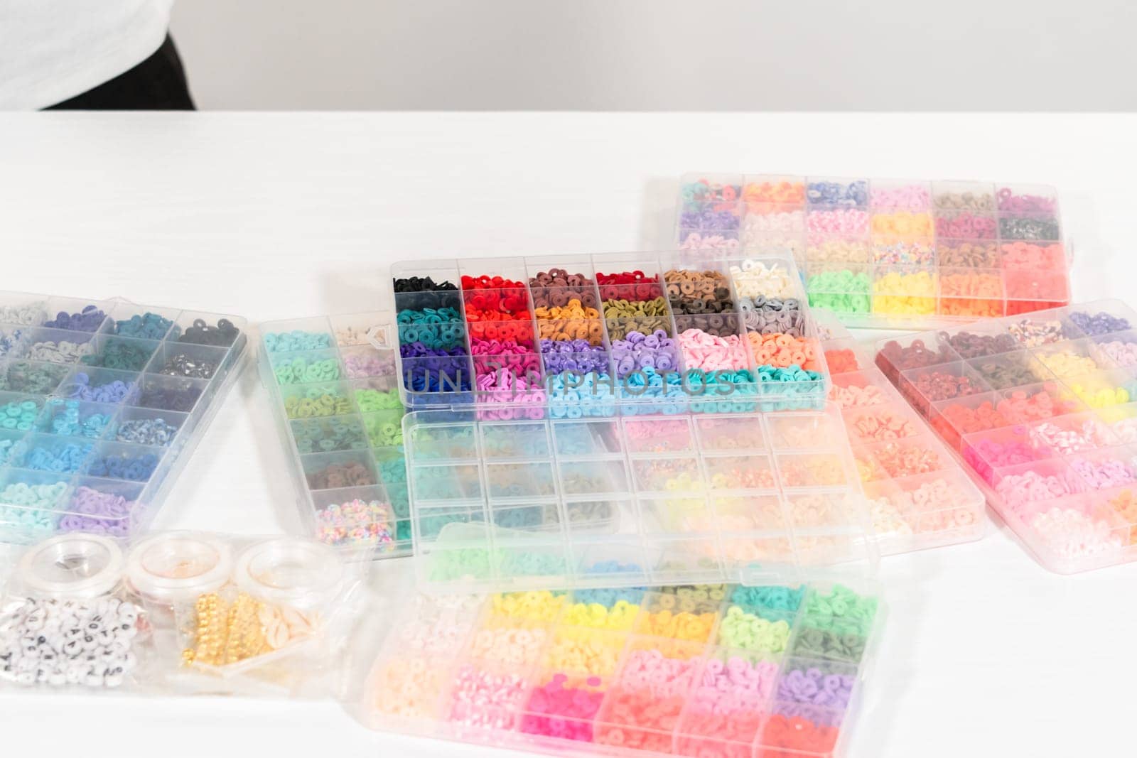 Assorted clay bead boxes neatly arranged on a white table, awaiting a creative kids' craft project.