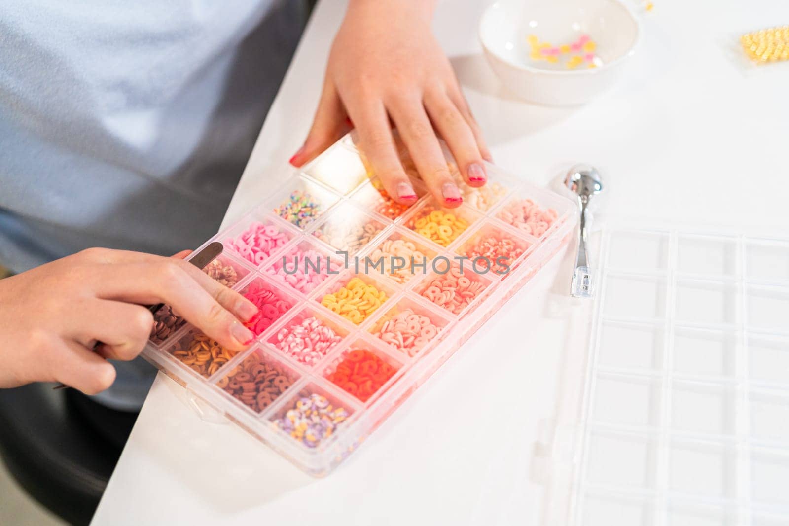 Little girl enjoys crafting colorful bracelets with vibrant clay beads set.