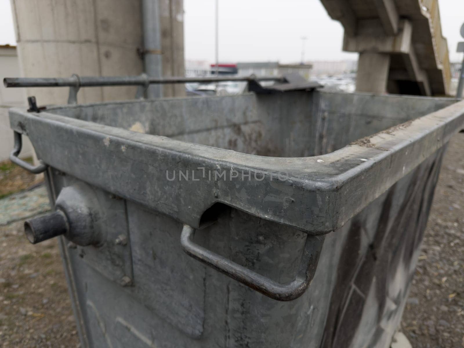 Close up photo of gray metal waste bin. Creation of trash cans on the street for cleanliness of city. Recycling waste after collecting it in special trash can. Old garbage cart for large garbage