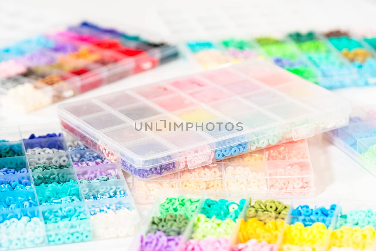 Assorted clay bead boxes neatly arranged on a white table, awaiting a creative kids' craft project.