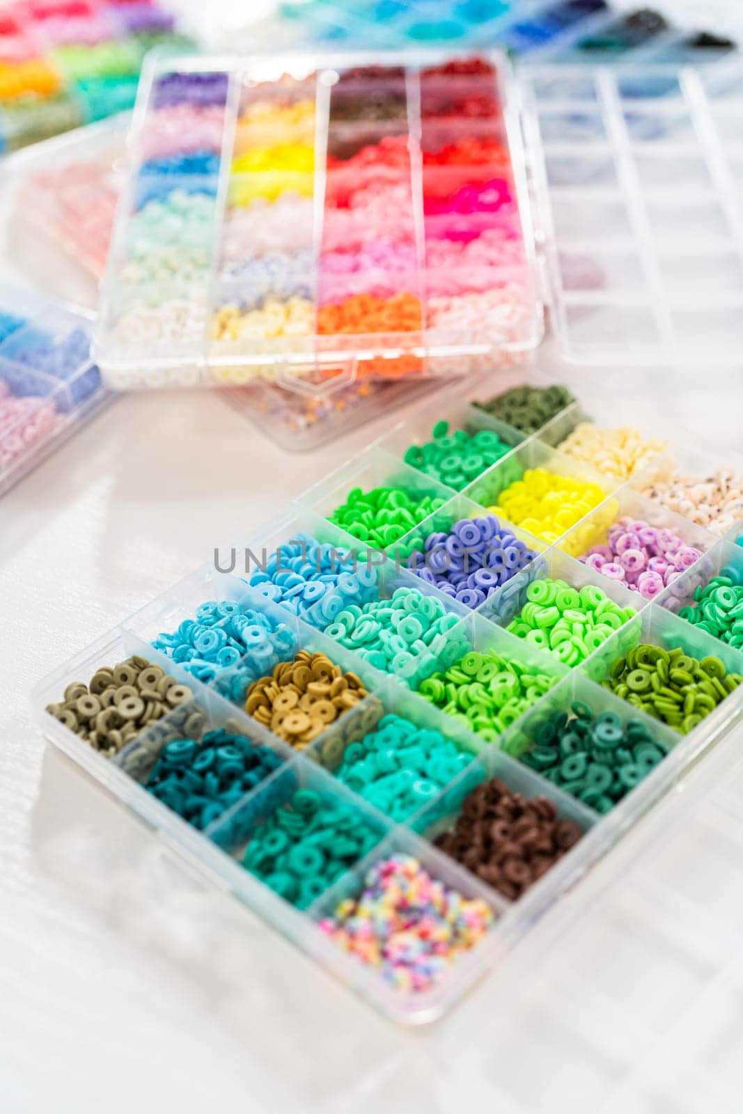 Assorted clay bead boxes neatly arranged on a white table, awaiting a creative kids' craft project.