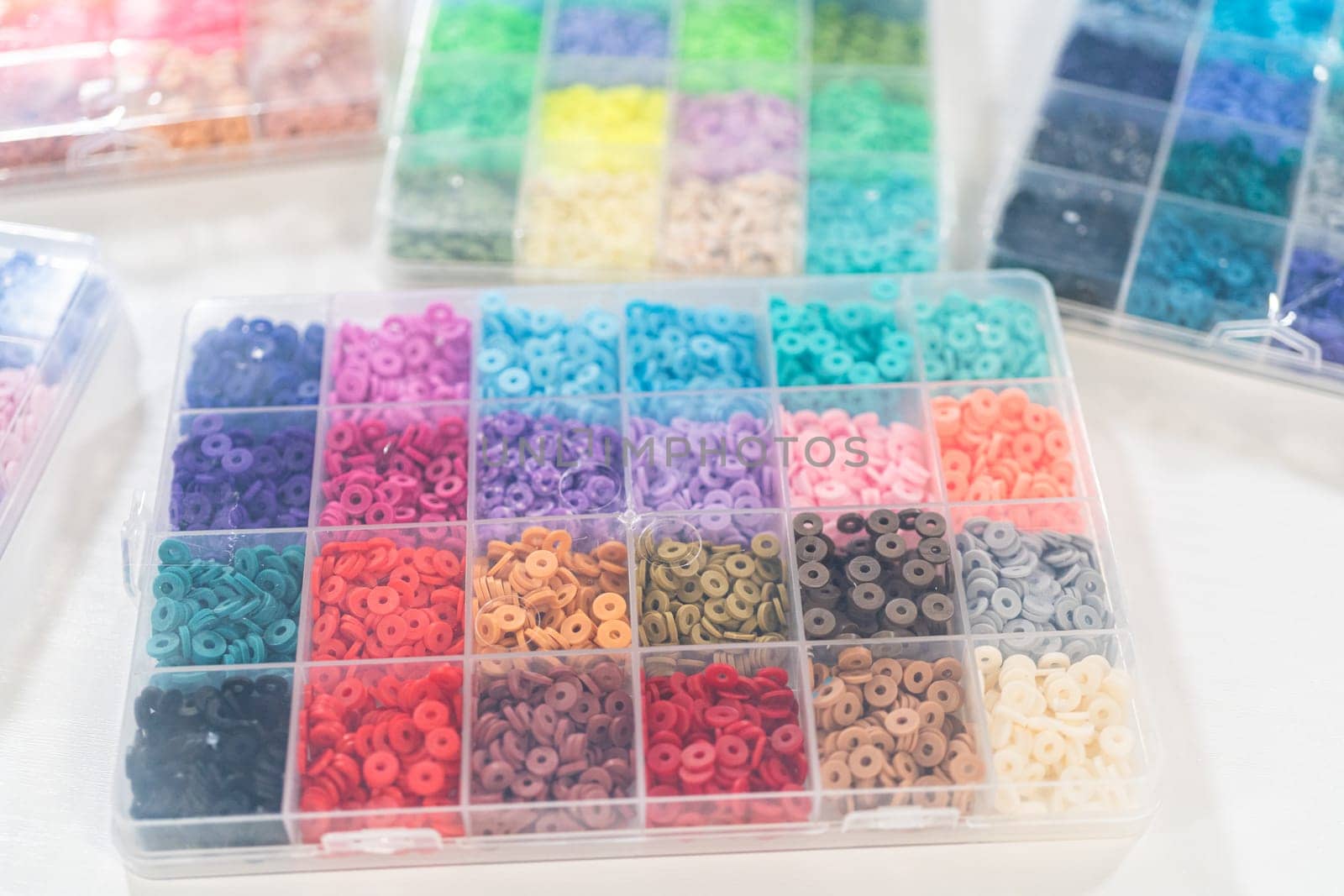 Assorted clay bead boxes neatly arranged on a white table, awaiting a creative kids' craft project.