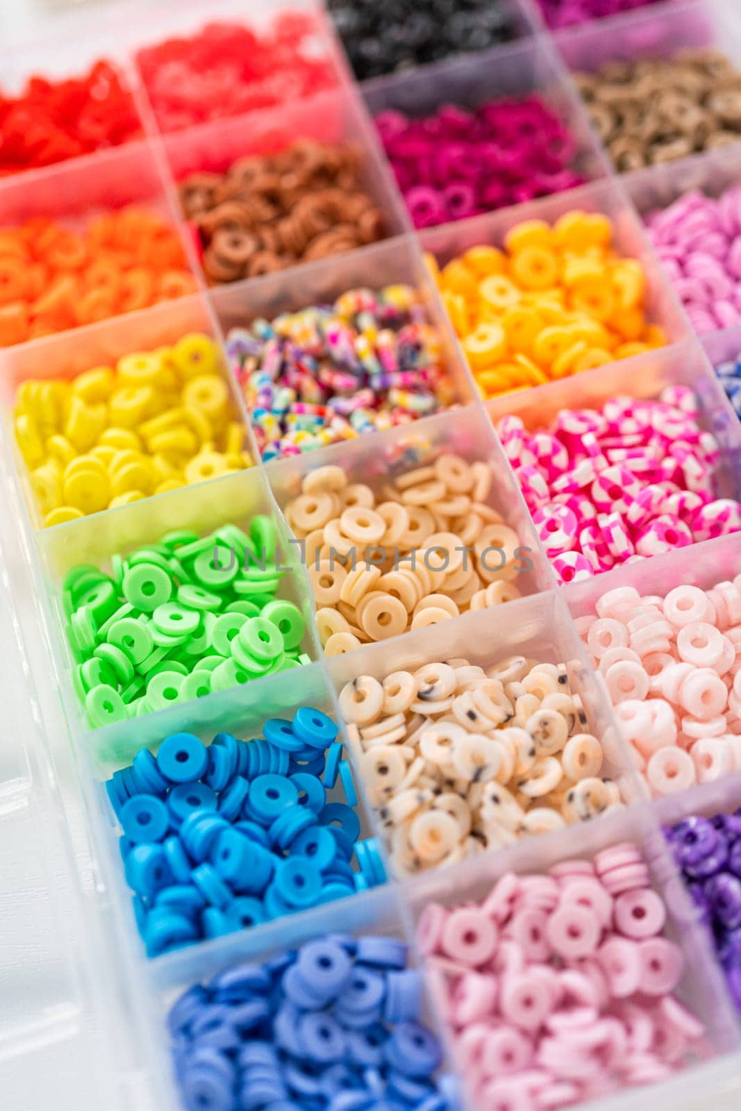 Assorted clay bead boxes neatly arranged on a white table, awaiting a creative kids' craft project.