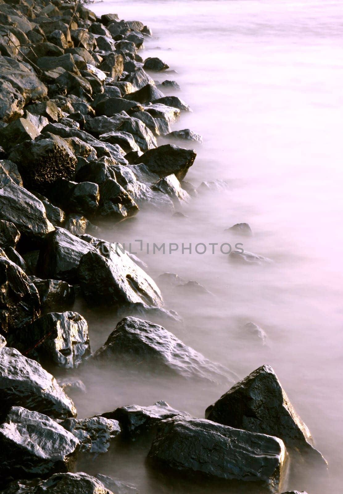 Shore fortification lapped by waves. Long exposure with neutral density filter