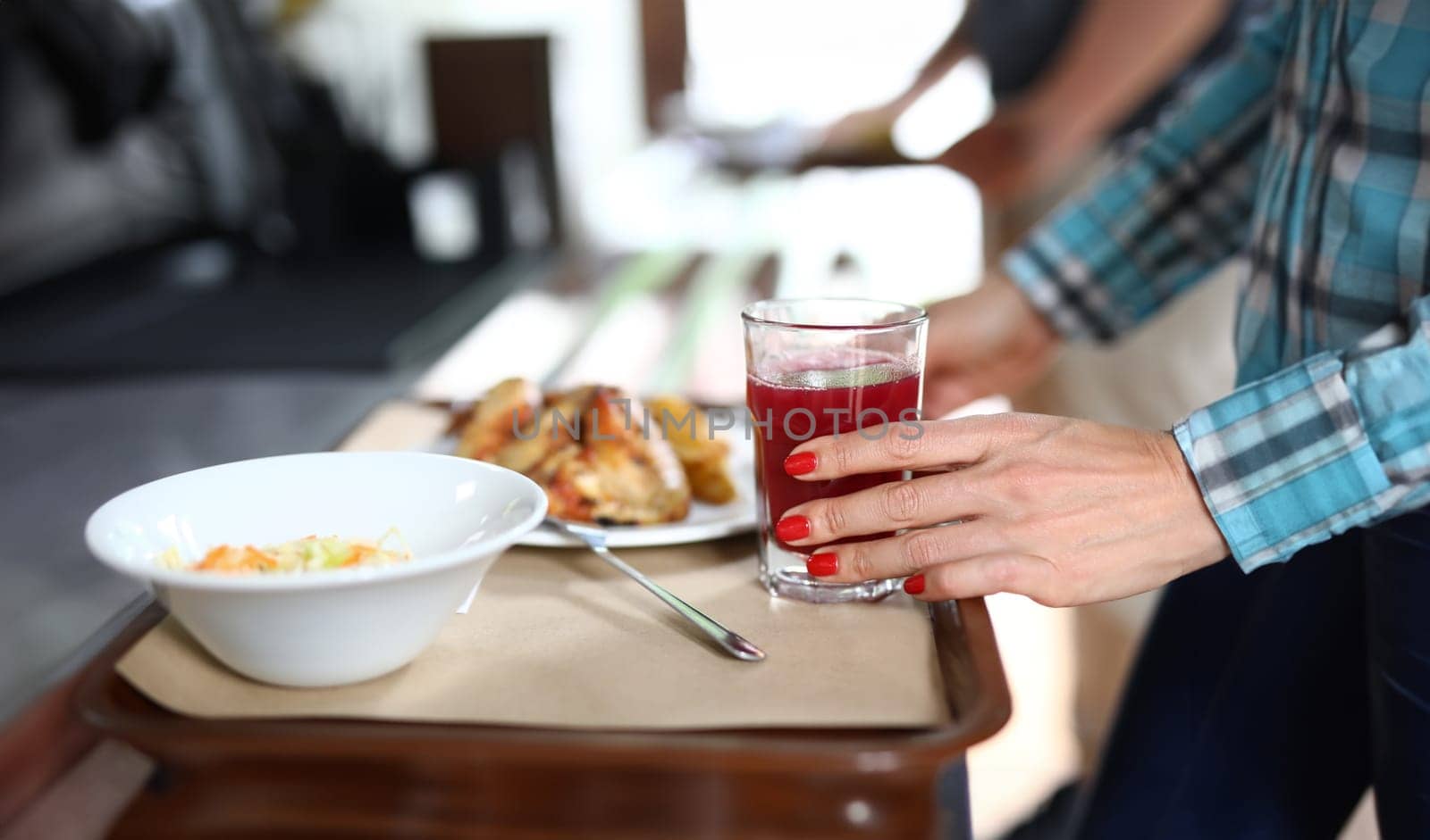 On tray are plates with dinner dishes, female hand holds glass of red liquid. Self service in bistros and restaurants concept