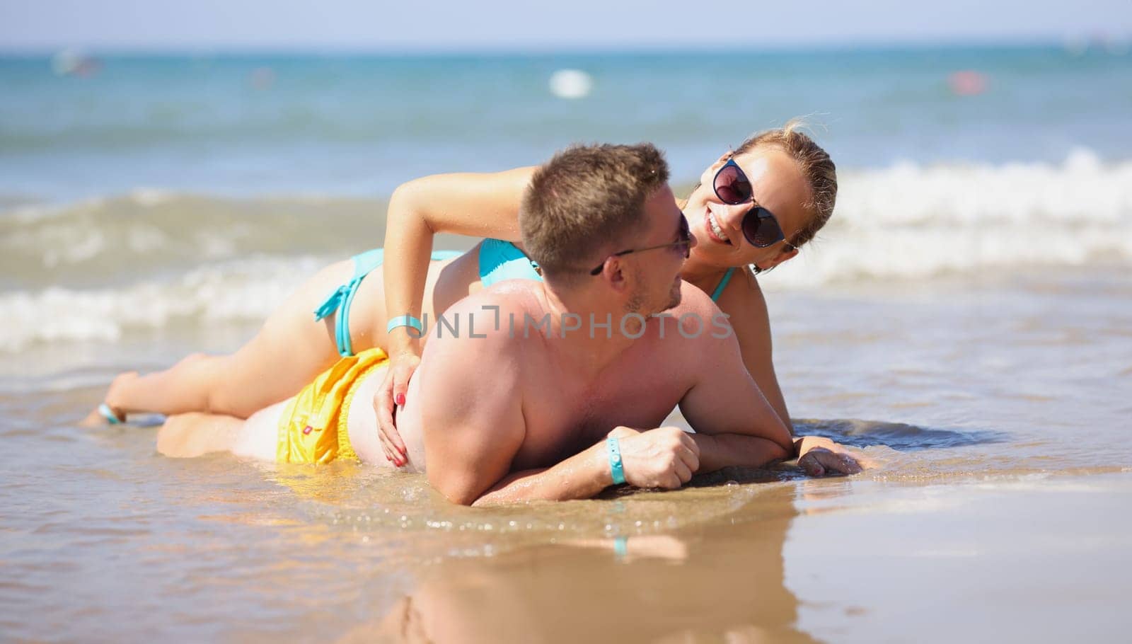 Smiling man and woman lie on beach by kuprevich