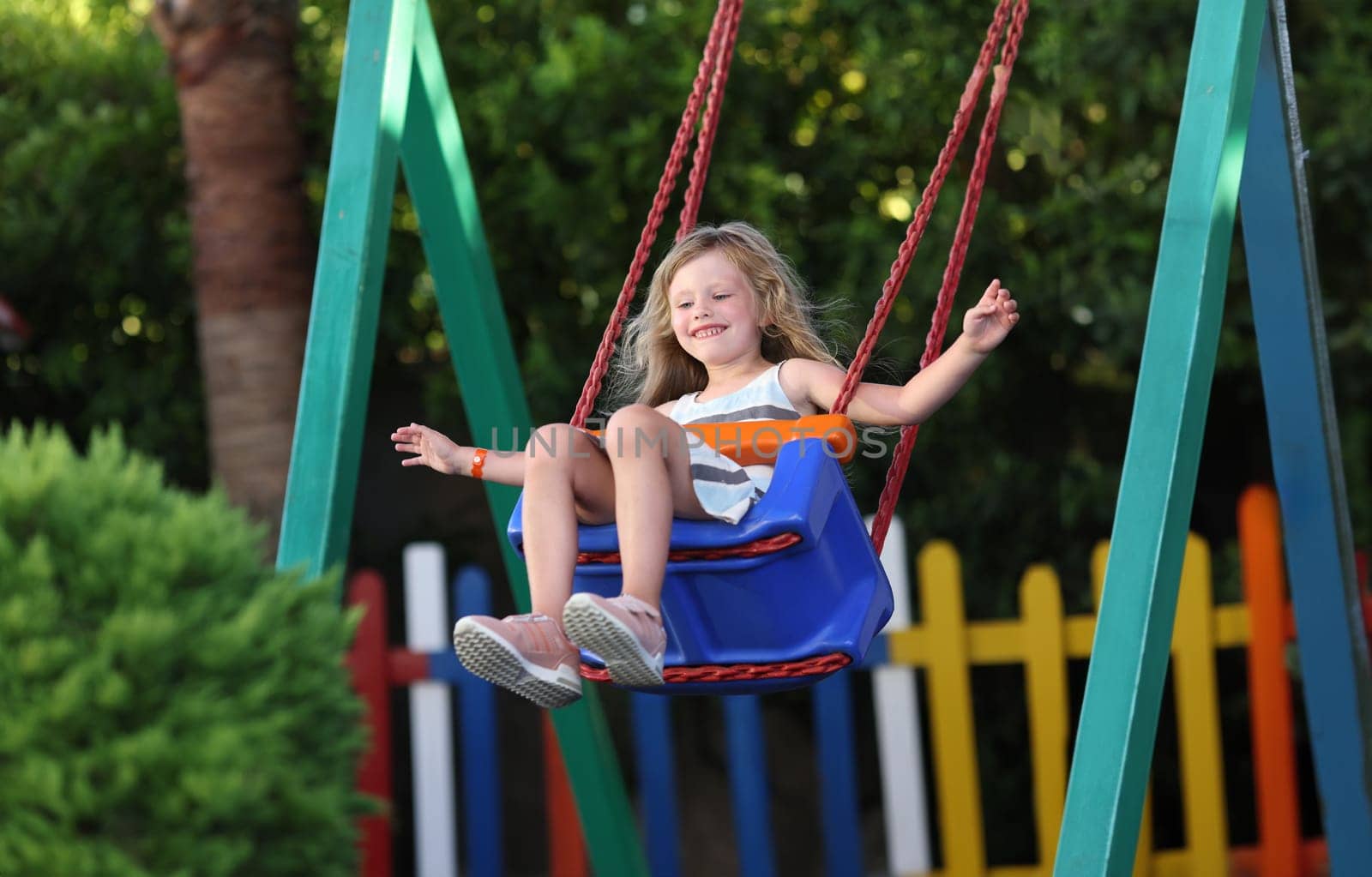 Happy little girl swinging on swing concept by kuprevich