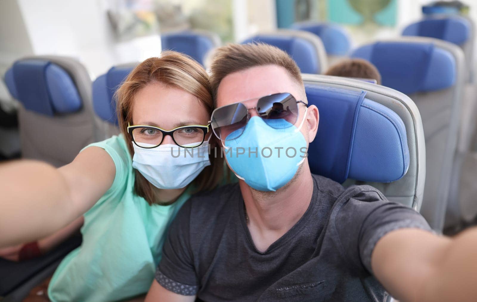 Man and woman wearing medical protective masks on plane. Safe travel to coronavirus pandemic concept
