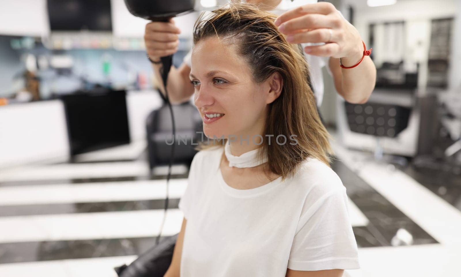 Woman in a beauty salon dry her head with hairdryer. Hair styling training concept