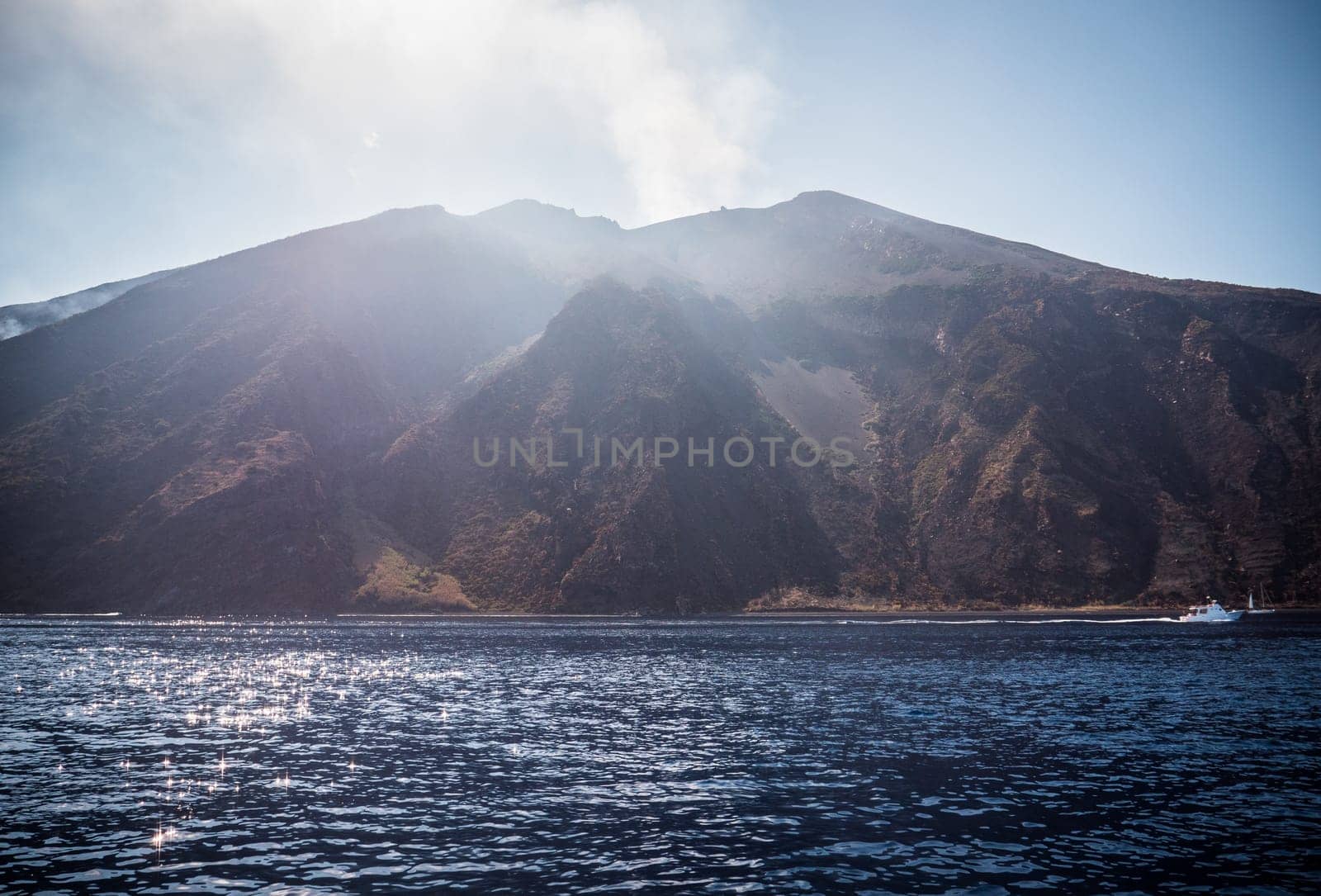 The sun shines on the mountains above the water