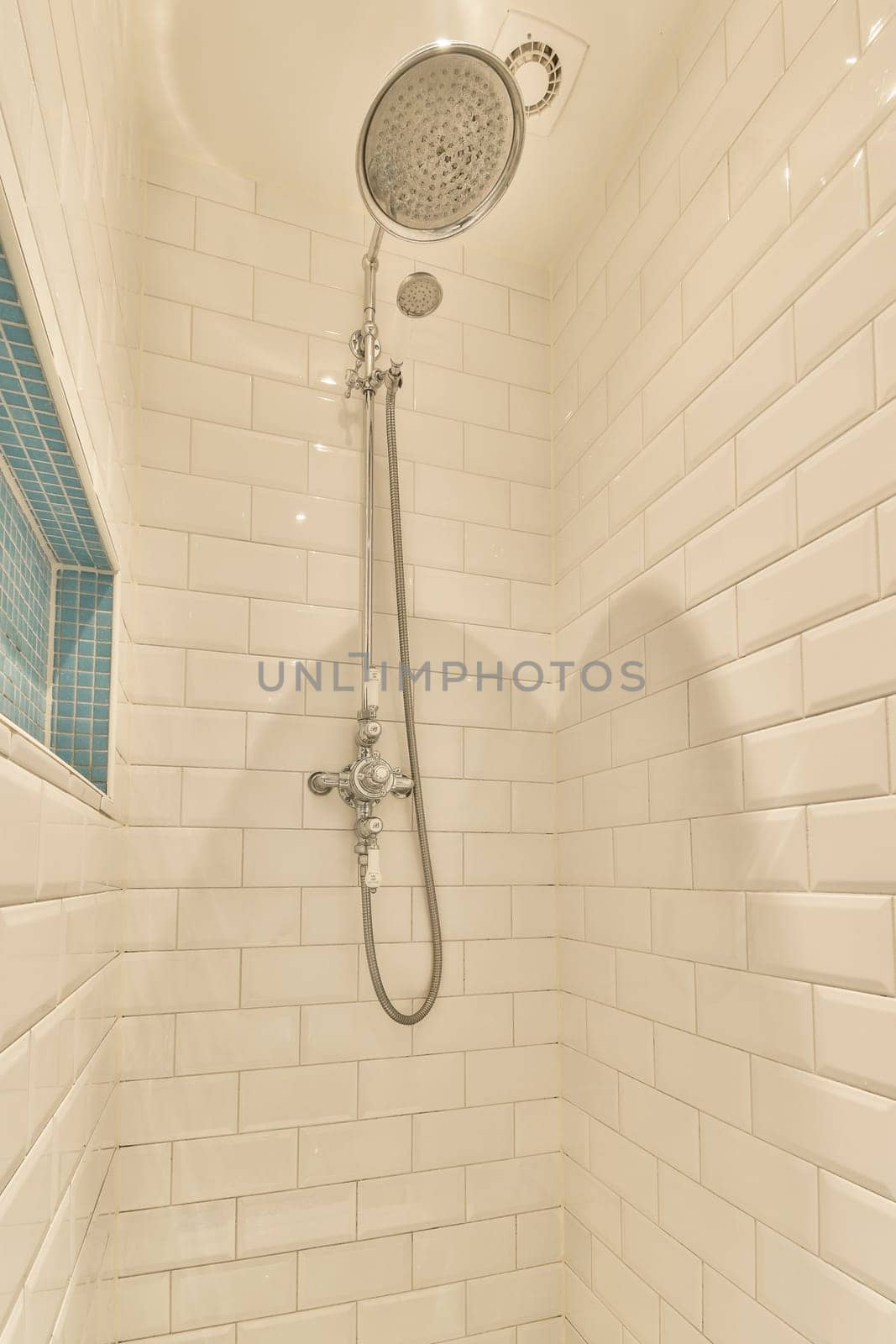 a shower with white subway tiles and a shower head by casamedia