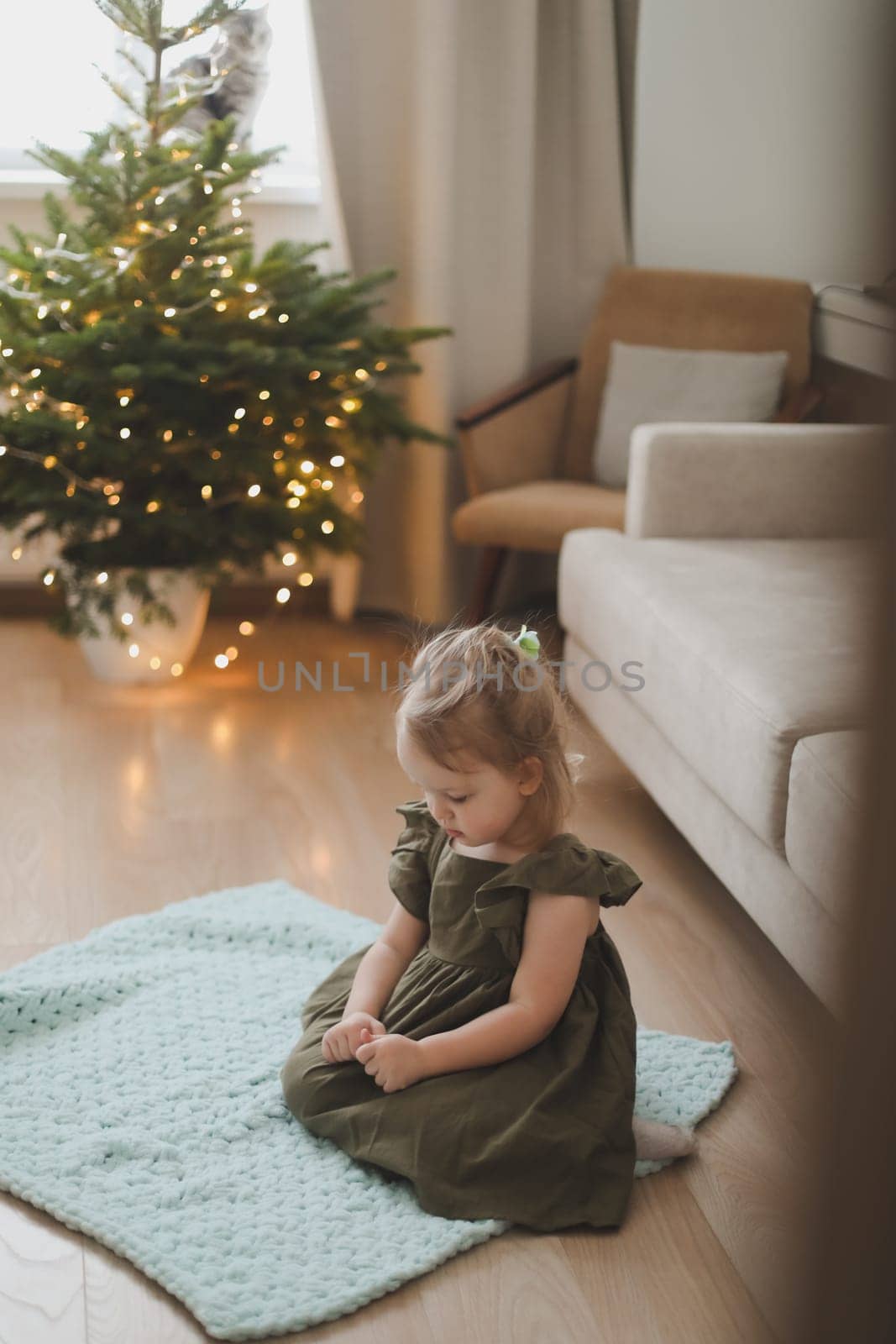 Little girl decorating christmas tree with toys and baubles. Cute kid preparing home for xmas celebration