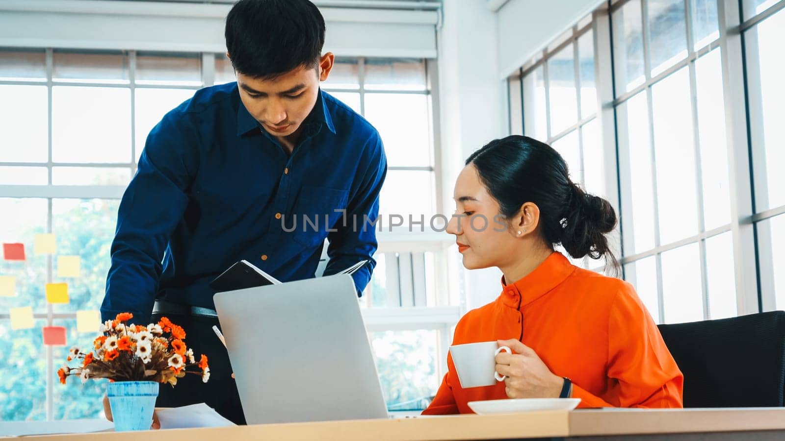 Two business people talk project strategy at office meeting room. Businessman discuss project planning with colleague at modern workplace while having conversation and advice on financial report. Jivy