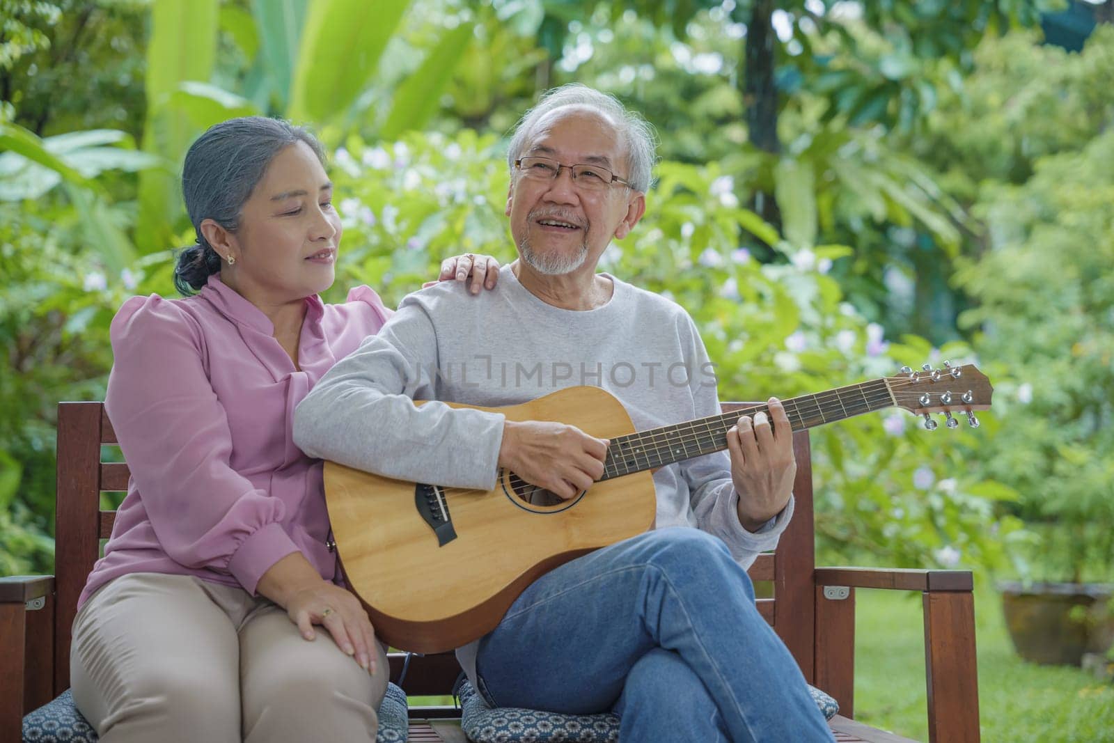 Asian senior couple elderly man playing guitar while his wife singing together outdoors at house, Activity family health care, Enjoying lifestyle during retirement life having fun of senior older