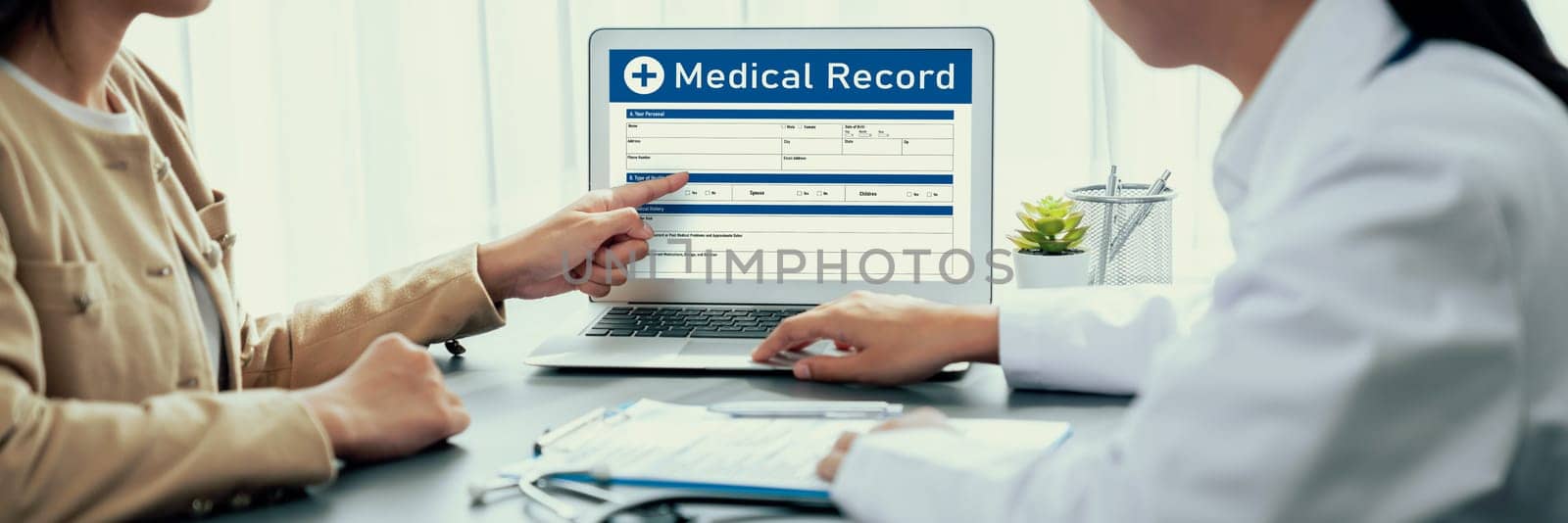 Doctor show medical diagnosis report on laptop and providing compassionate healthcare consultation while being supportive and holding young patient hand in doctor clinic office. Neoteric