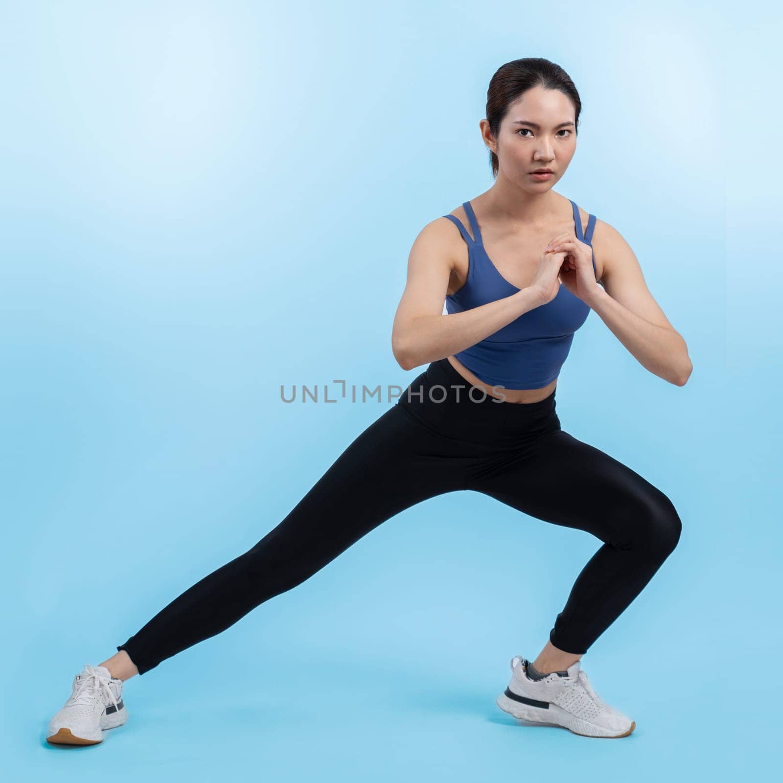 Young attractive asian woman in sportswear stretching before fitness exercise routine. Healthy body care workout with athletic woman warming up on studio shot isolated background. Vigorous