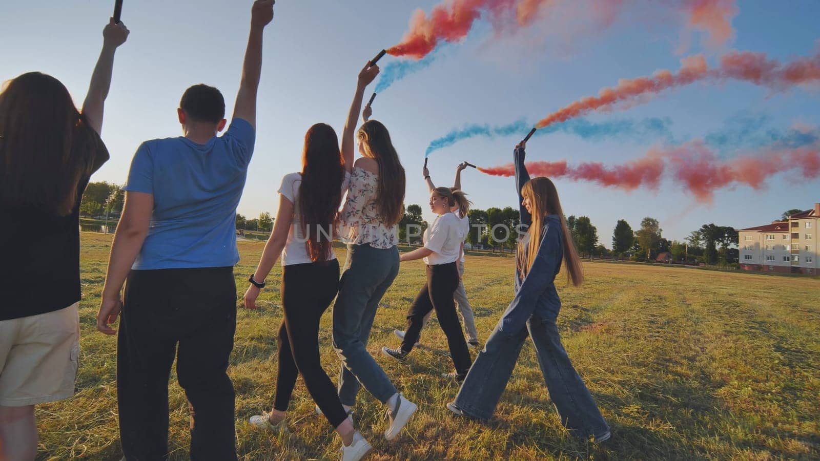A group of friends spraying multi-colored smoke at sunset. by DovidPro