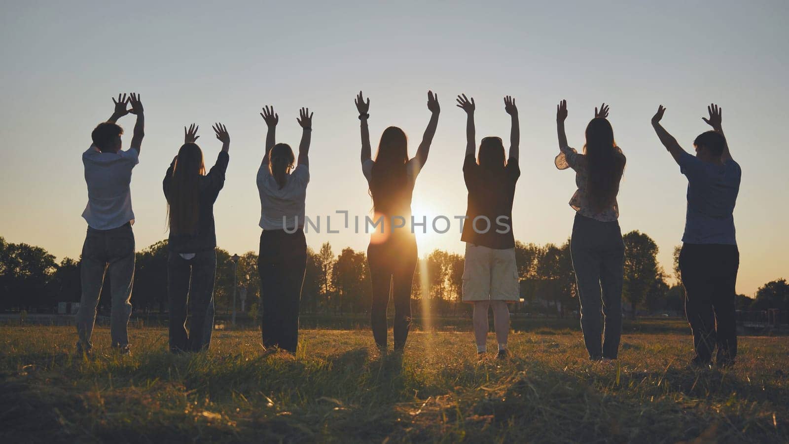 Seven friends waving at the sunset