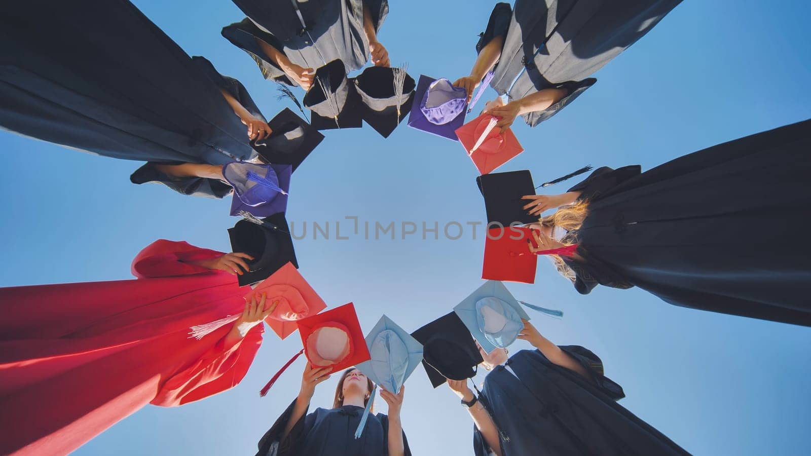 College graduates make a circle shape out of their colorful hats