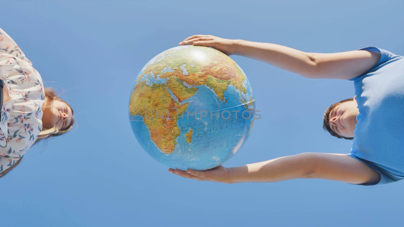 A girl and a guy holding geographical a globe of the world. The concept of peace and creation