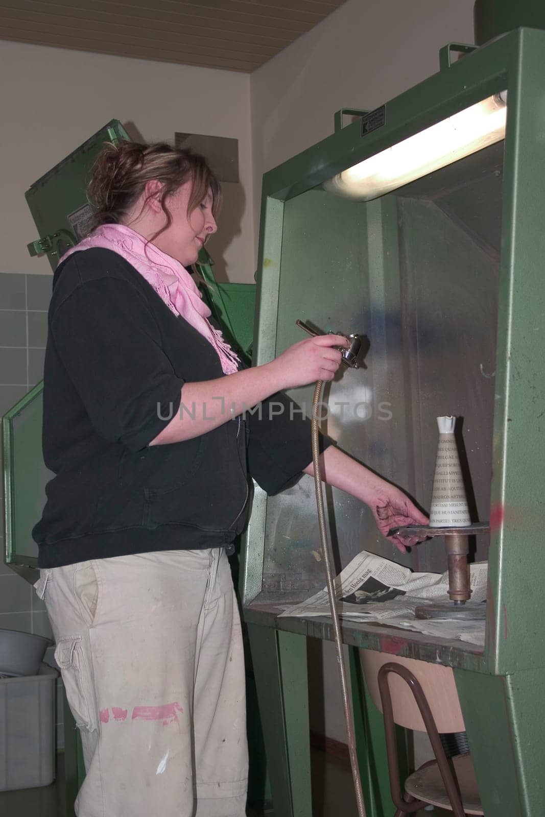 Vocational school student painting a porcelain container with spraying technique