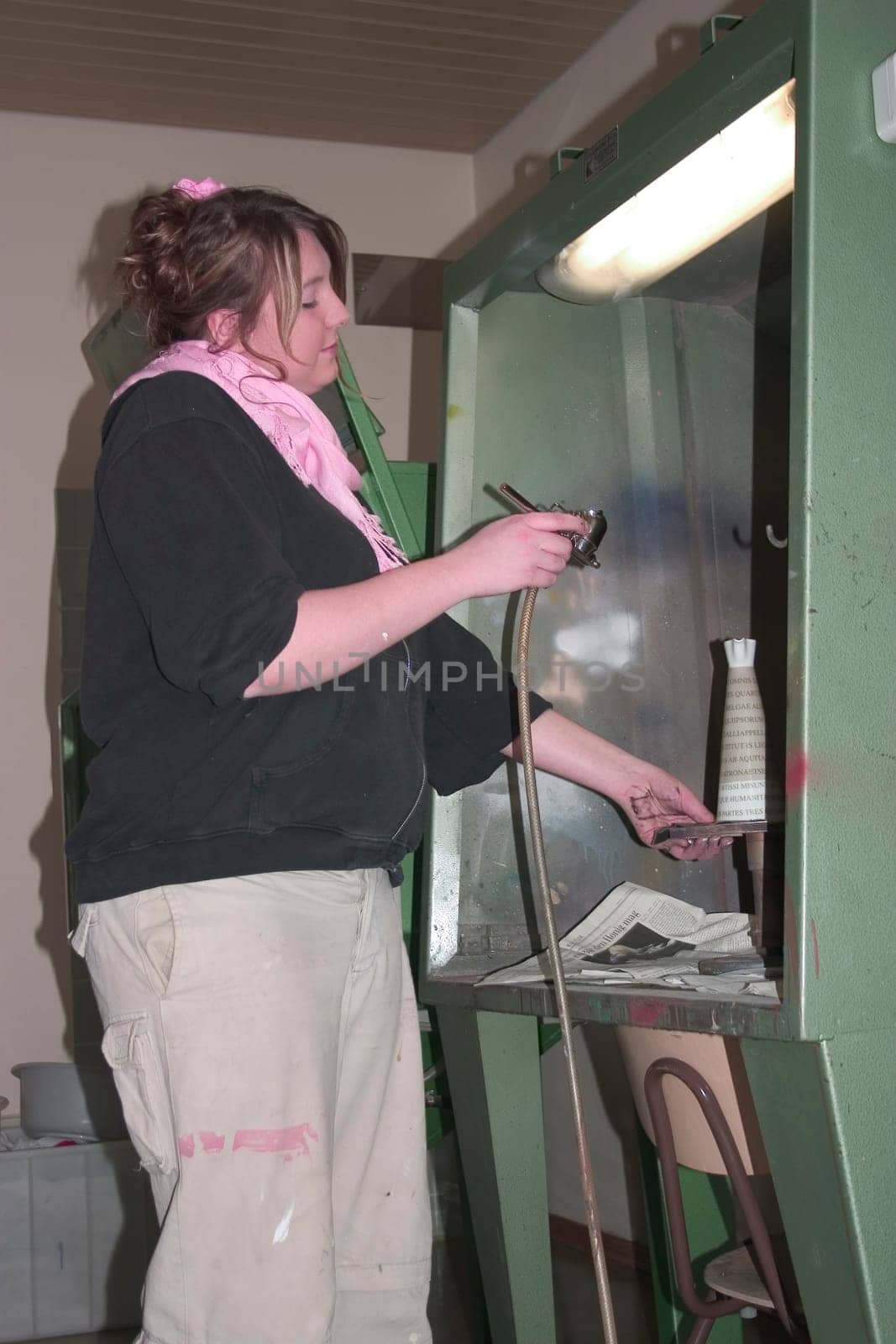 Vocational school student painting a porcelain container with spraying technique
