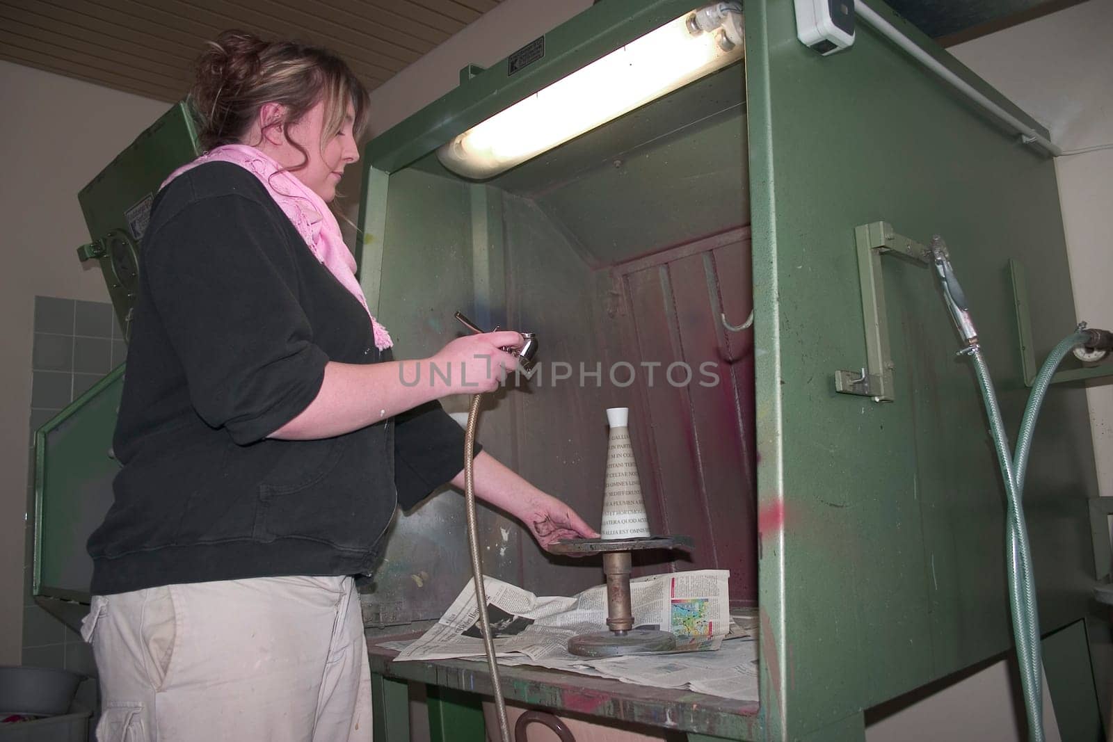 Vocational school student painting a porcelain container with spraying technique