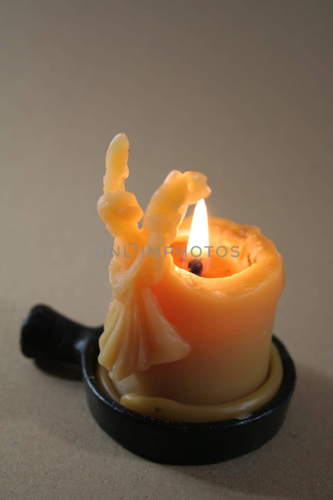 Flame shines through glowing angel in natural wax
