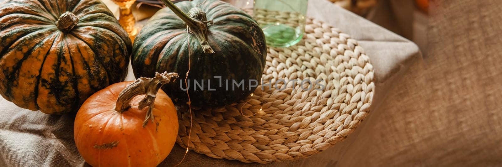Autumn interior: a table covered with dishes, pumpkins, a relaxed composition of Japanese pampas grass. Interior in the photo Studio. Close - up of a decorated autumn table