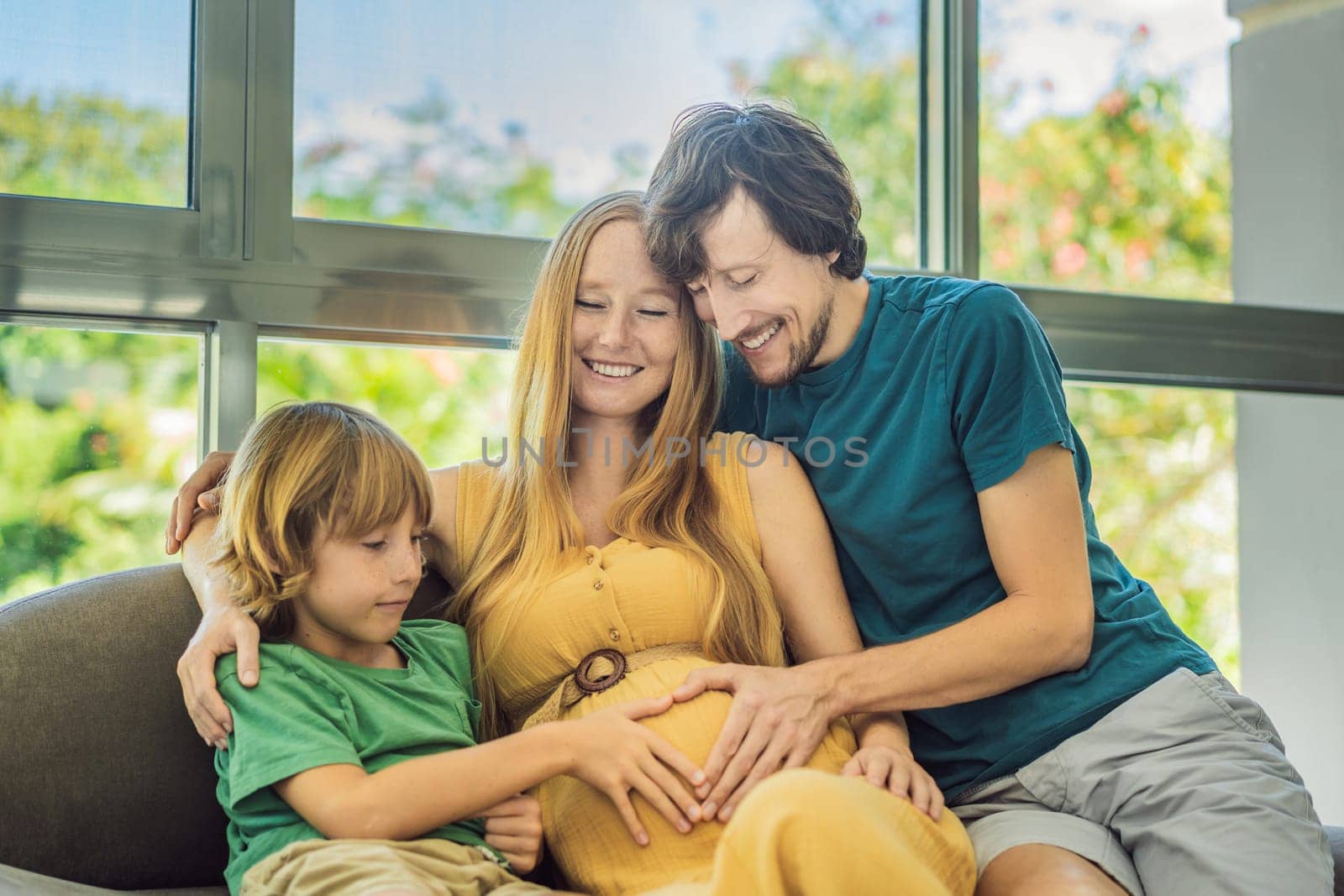 Expectant parents, mom, dad, and their eldest son share a heartwarming moment on the sofa, discussing the exciting journey of pregnancy by galitskaya