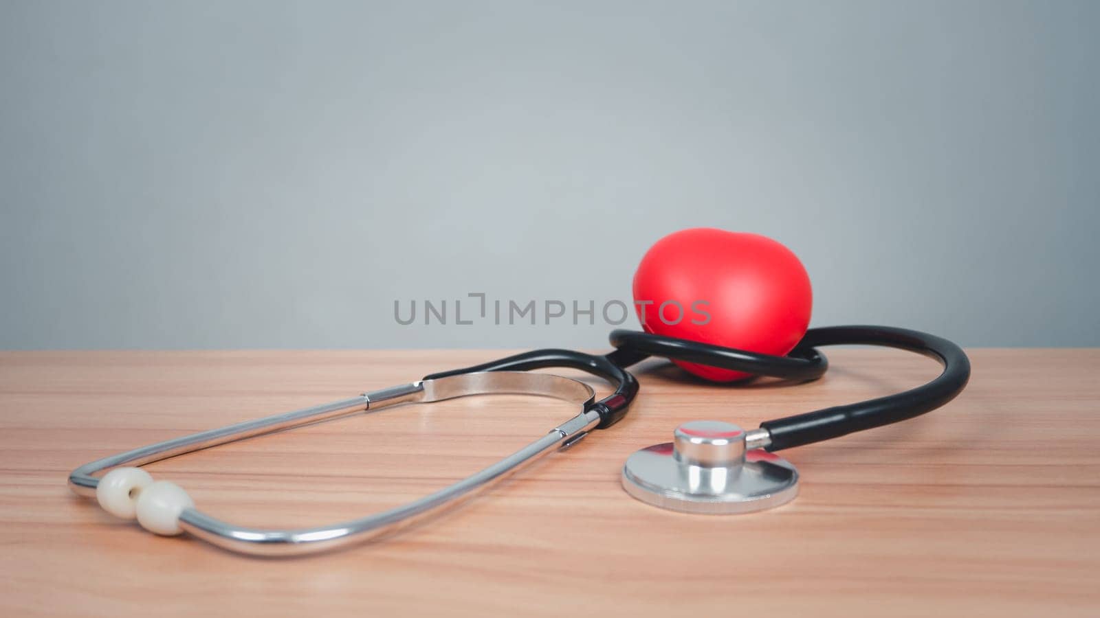 Red heart with headphones on a wooden table background. Medical and healthcare concepts.