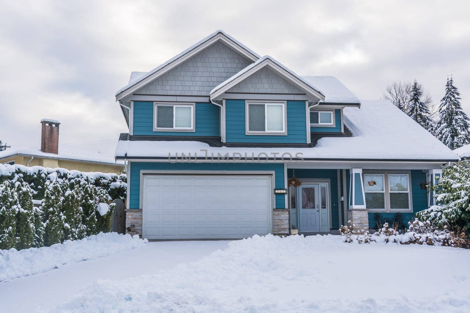 Family house with front yard in snow. Residential house on winter cloudy day