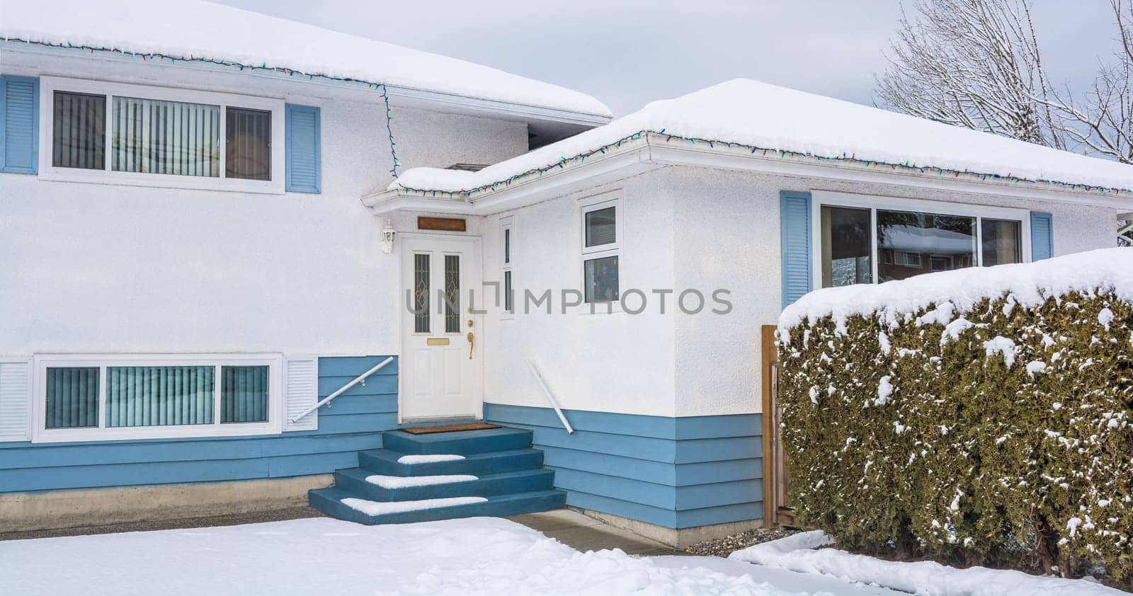 Family residential house with front yard in snow. Beautiful North American house on winter cloudy day
