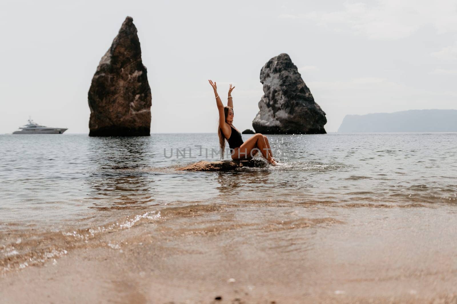 Woman summer travel sea. Happy tourist enjoy taking picture outdoors for memories. Woman traveler posing on the beach at sea surrounded by volcanic mountains, sharing travel adventure journey by panophotograph