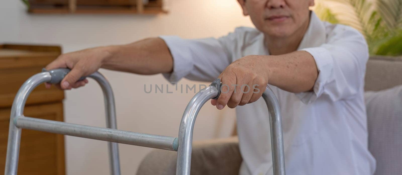 Asian woman caregiver helping senior man walking. Nurse assisting he old man patient at nursing home. Senior man using walker being helped by nurse at home. Elderly patient care and health lifestyle by wichayada