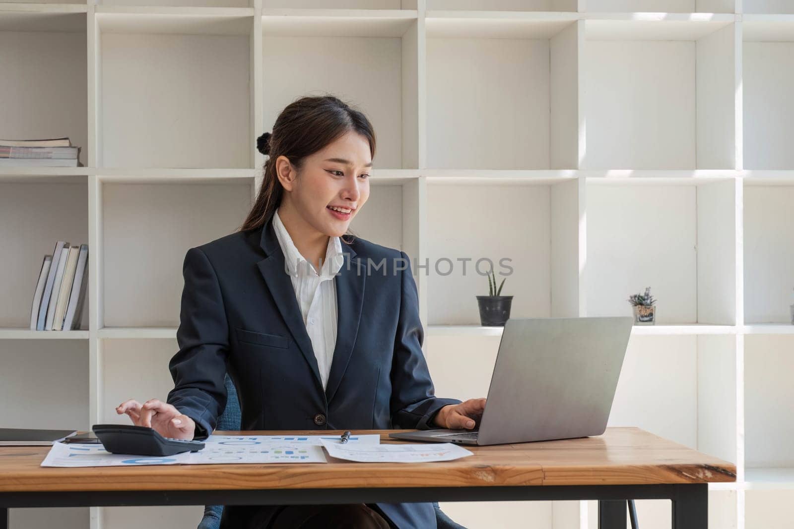 businesswoman using calculator for do math finance on wooden desk in office and business working background, tax, accounting, statistics and analytic research concept by wichayada