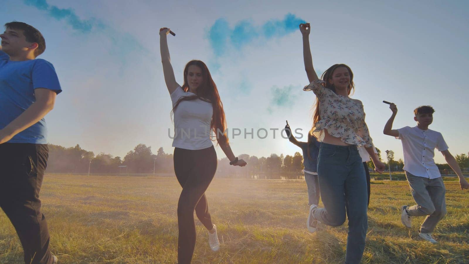 A group of friends spraying multi-colored smoke at sunset. by DovidPro