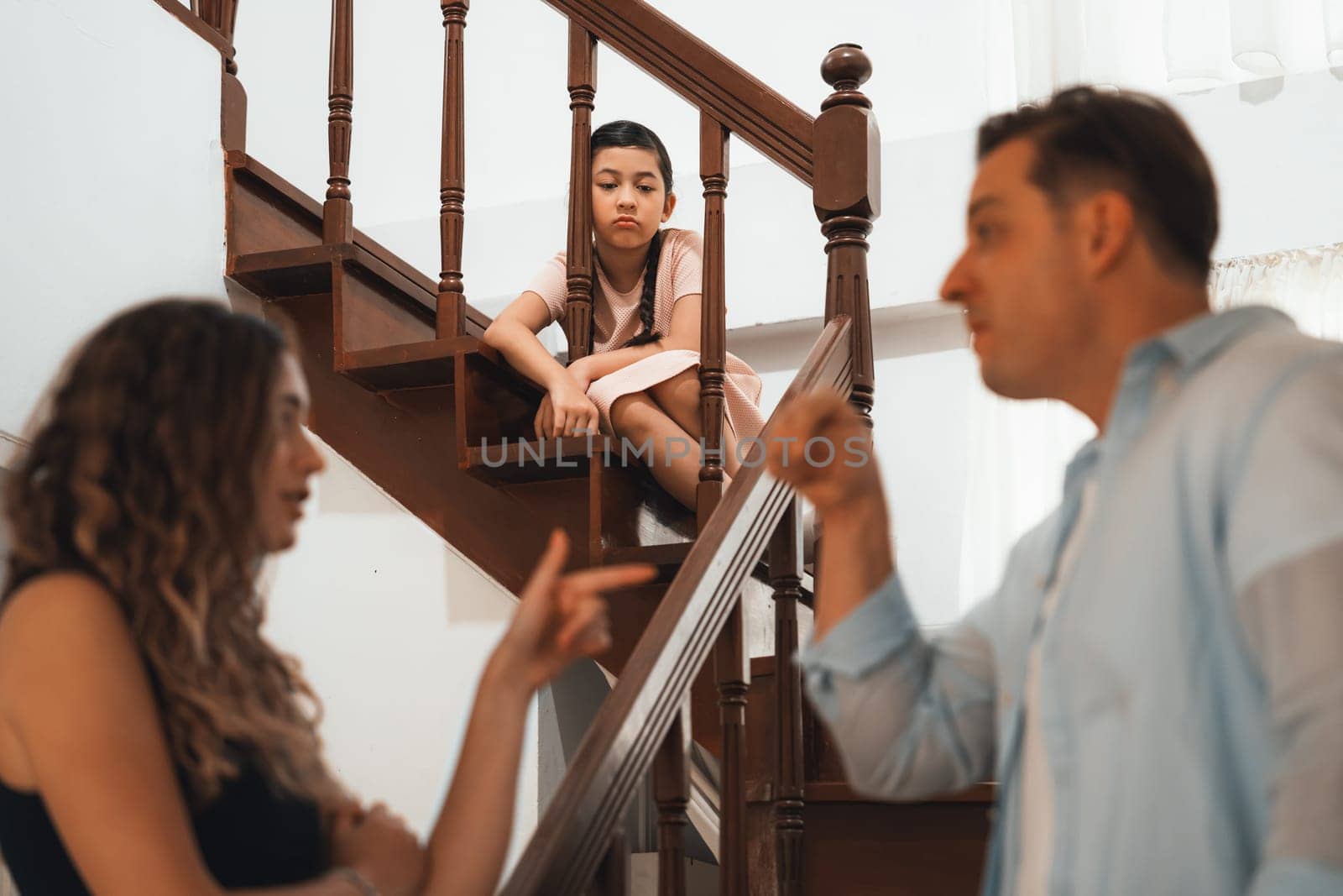 Stressed and unhappy young girl watch her parent arguing from the stair. Domestic violence at home and traumatic childhood develop to depression and anxiety. Unhealthy family concept. Synchronos