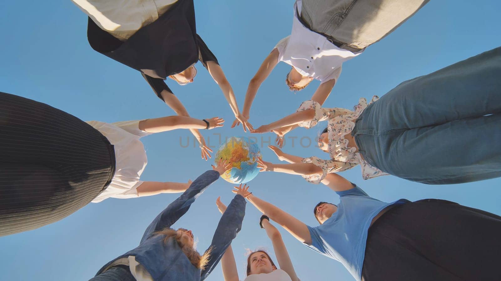 Friends hold and toss a geographic globe in their hands. The concept of keeping the world safe