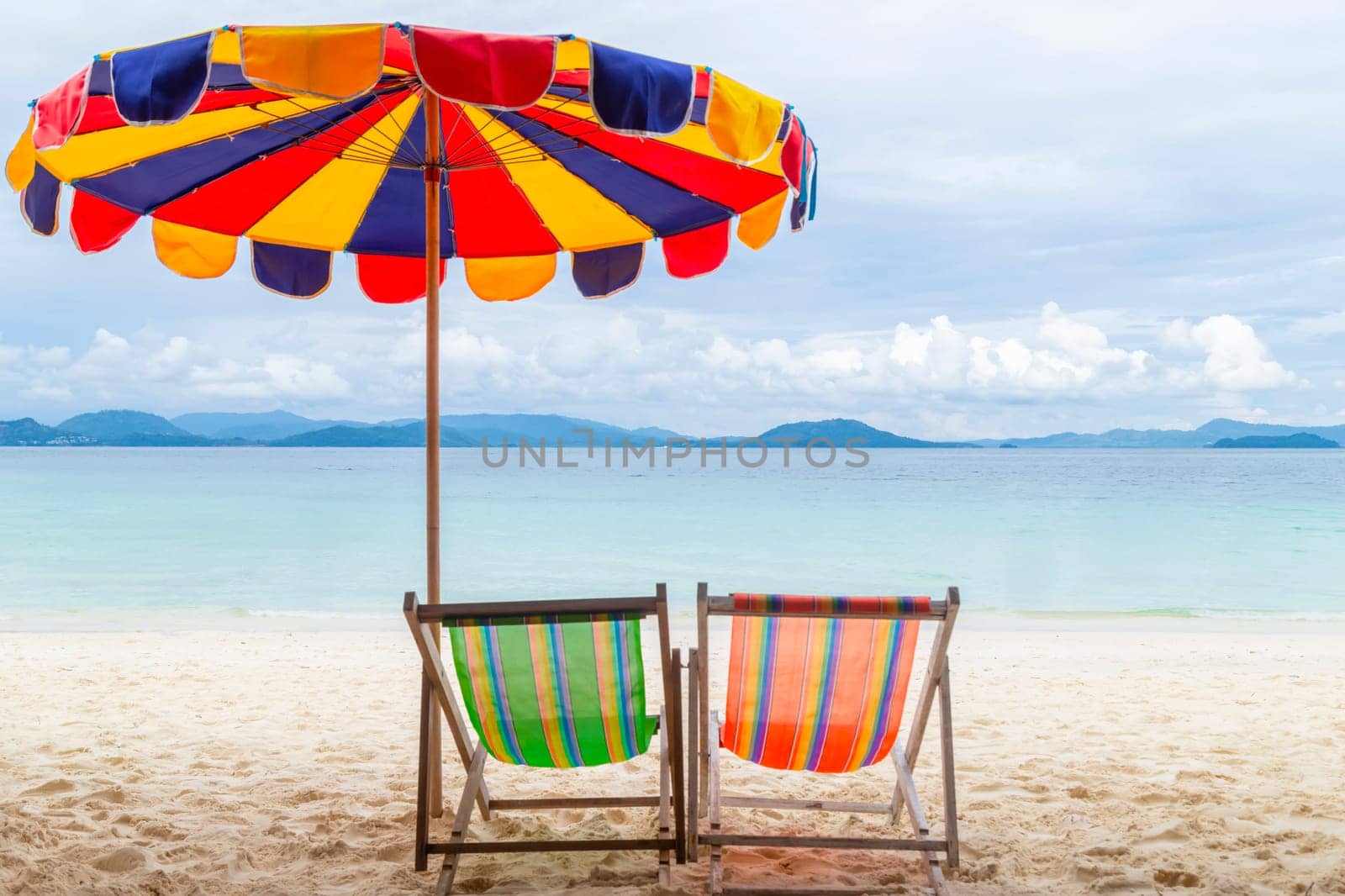 Still life shot of two deck chairs under an umbrella on the beach