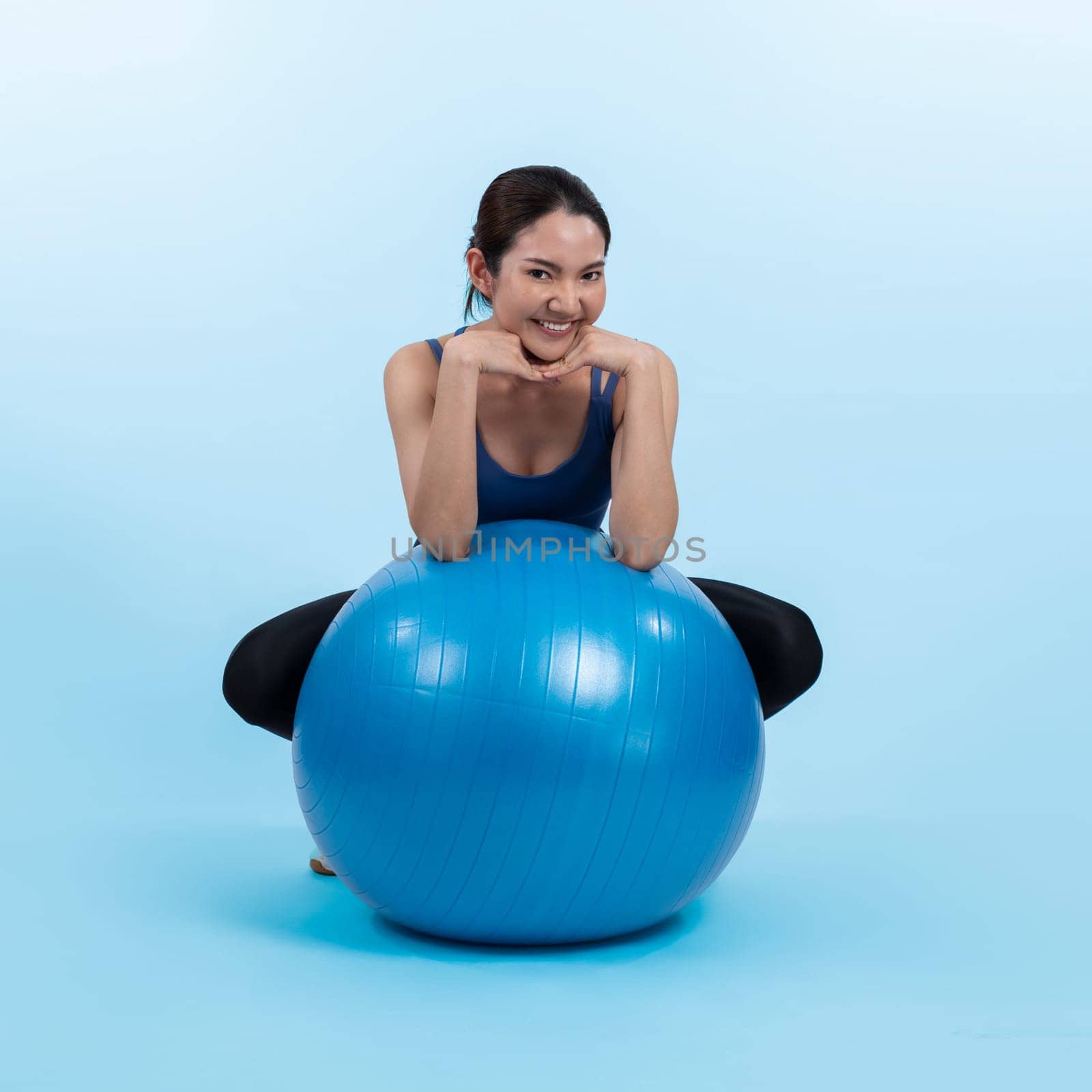 Young attractive asian woman portrait in sportswear with fit ball targeting on abs muscle for effective energetic daily workout routine. Studio shot and isolated background. Vigorous