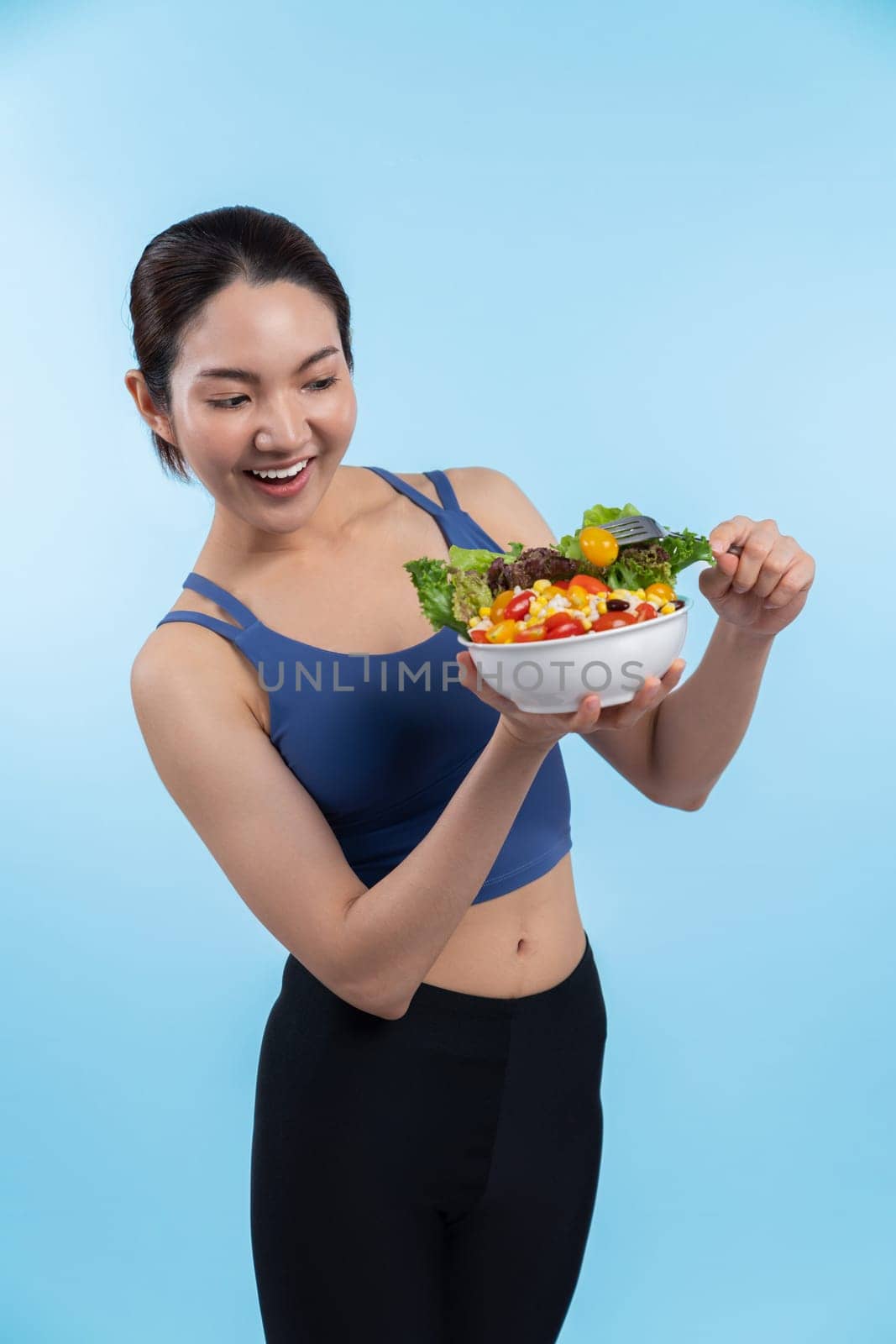 Asian woman in sportswear holding salad bowl on isolated background. Vigorous by biancoblue