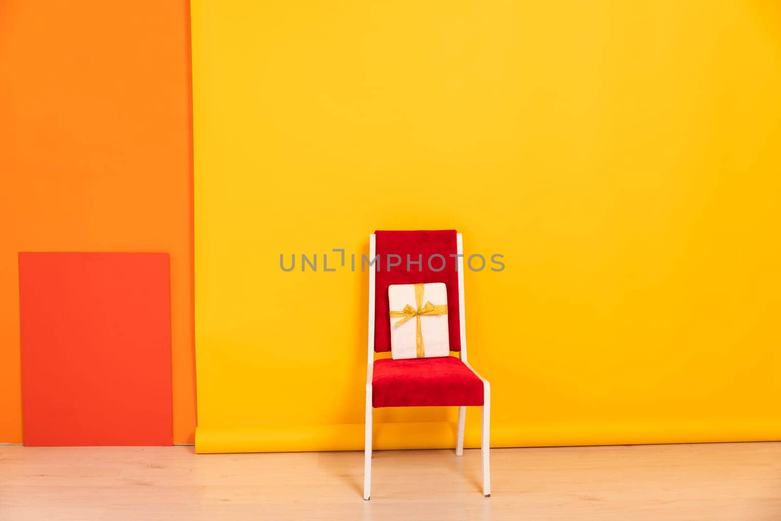 chair with gift in interior on yellow background